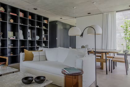 "Para equilibrar el frente oscuro, incorporamos géneros claros”, dice la arquitecta Mosteiro. Sillones (Dharma Deco). Mesa de acrílico (Ries). Mesas bajas con tapa de terrazo (diseño de Estudio MMS). Lámpara de pie (Iluminación Agüero).