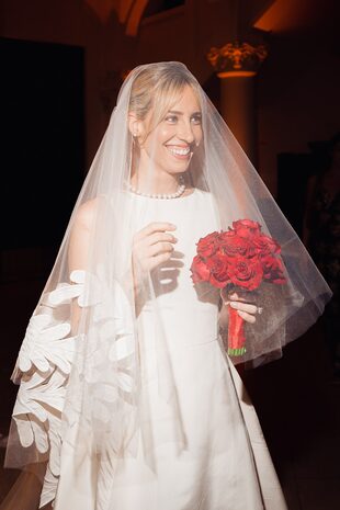 Para la ceremonia, Grace llevó un vestido con cuello a la base y velo de Oscar de la Renta que acompañó con un bouquet de rosas rojas.