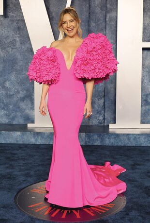 Para la fiesta de Vanity Fair, Kate Hudson eligió un vestido fucsia de corte sirena, escote pronunciado y mangas abultadas de Tamara Ralph. Combinó el look con zapatos de Giuseppe Zanotti.