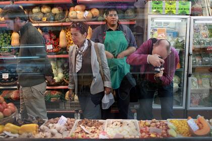 PARA LA FOTO. Turistas extranjeros toman fotografías de la variedad de verduras que se exhiben en un puesto de la feria de Belgrano