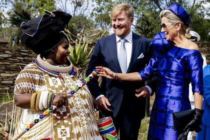 Para la jornada más formal de la visita, la ceremonia de bienvenida en los Edificios de la Unión y la visita a Freedom Park, Máxima estrenó un estilismo deslumbrante: vestido de escote asimétrico con una escultural manga en forma de rosa, realizada en seda mikado a cuadros por Natan e inspirado en los clásicos diseños africanos conocidos como Kanga. Lo combinó con un sombrero pillbox de la misma tela, zapatos Gianvito Rossi, clutch a tono, también de Natan Couture, y joyas de la firma Jar.