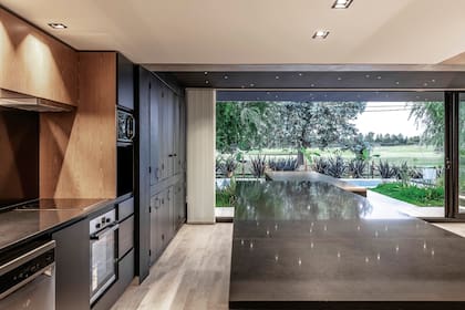 Para las mesadas de cuarzo de la cocina y de la isla ‘Taurus Black’ (todo de TechniStone), también se eligió un acabado brillante, pero negro. La apertura al golf hace olvidar la proximidad con las casas vecinas.