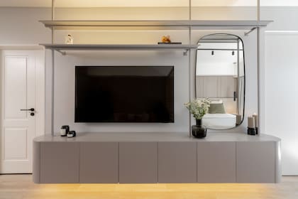 Para las paredes eligieron un tono gris claro, que se replicó en el rack TV flotante (Estudio Aldo). Espejo (Aura Home) y objetos decorativos (Organizza).