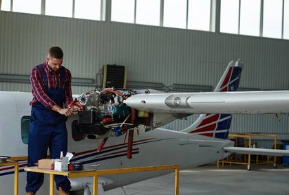 Young man repairing airplane in hangar