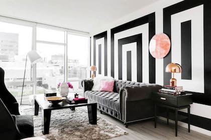 Para salir de lo tradicional, en este living se apostó a una pared con motivos rectangulares que ponen en acción el contraste del blanco y el negro