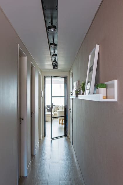Para vestir el pasillo, y al no haber espacio para un mueble, se hicieron dos estantes de MDF laqueado donde descansan cuadros, plantas y objetos.