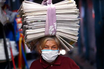 Guillermina de Figueredo, de 72 años, balancea periódicos reciclados en su cabeza que vende a comerciantes que los usan como envoltorios