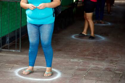 Las personas se paran en áreas designadas mientras esperan en la fila para obtener alimentos básicos gratuitos en la escuela primaria de Santa Ana en Asunción