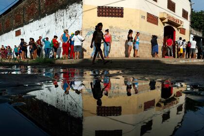 Los vecinos hacen fila para obtener alimentos básicos gratuitos fuera de la escuela primaria de Santa Ana