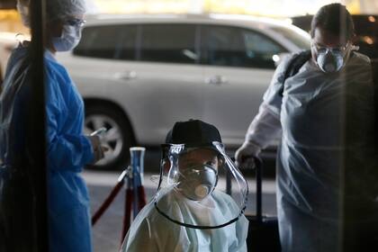Matias Morel y su tía Stefanie Ruiz Díaz, pasan un punto de control de temperatura a su llegada al aeropuerto Silvio Pettirossi en Luque para tomar un vuelo a Miami