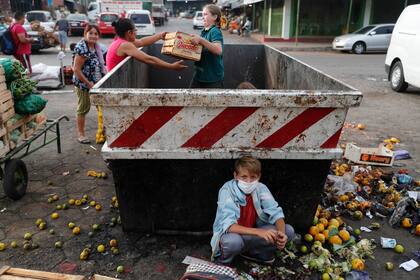 Con su familia, Fabián Ramírez, de 11 años, recolecta vegetales de un contenedor de basura desechados en el "Mercado de Abasto"