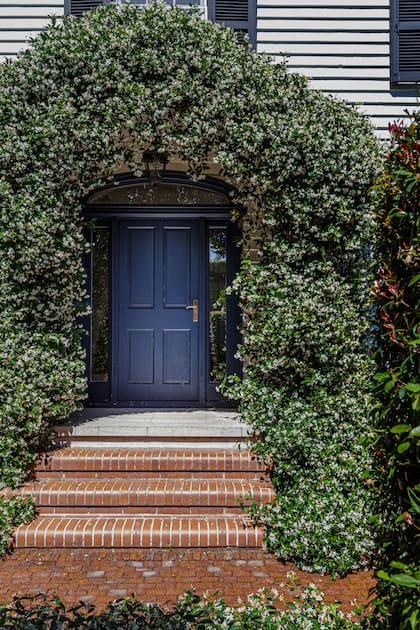 Parece una postal norteamericana, pero está en Buenos Aires. Paredes con siding, una puerta rodeada de vidrio y la enredadera que enmarca prolijamente