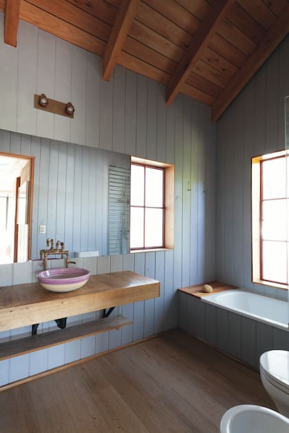 Paredes pintadas en ‘Azul Tormenta’ (Sherwin Williams), que queda muy bien con el rojo de las ventanas. El detalle: las griferías, hechas por el dueño de casa.