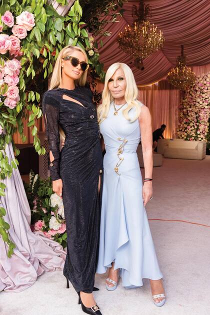Paris Hilton, con un vestido negro cut-out con aberturas también de Versace, posa con Donatella, que llevó un traje celeste con los característicos broches dorados de su firma.