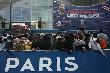 Paris Saint-Germain supporters gather outside the Parc des Princes stadium before Lionel Messi's press conference Wednesday, Aug. 11, 2021 in Paris. Lionel Messi finally signed his eagerly anticipated Paris Saint-Germain contract on Tuesday night to complete the move that confirms the end of a career-long association with Barcelona and sends PSG into a new era. (AP Photo/Rafael Yaghobzadeh)