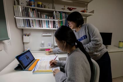 Park Euna lleva un vaso de agua a su hija mayor mientras estudia inglés en su habitación.