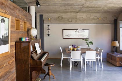 Parte de la pino tea recuperada de la obra reviste la pared que da apoyo a un antiguo piano catalán. Arriba, el cielo raso de hormigón exhibe artísticas formas caladas por Silvana.