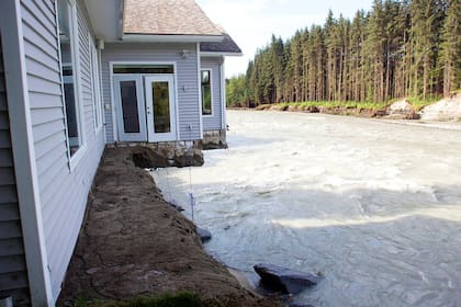 Parte de una casa en Riverside Drive sobresale de un terraplén, después de la erosión causada por la inundación récord del río Mendenhall, el sábado en Juneau, capital de Alaska