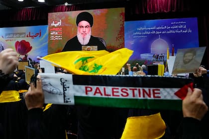 Partidarios de la milicia Hezbollah saludan con el puño en alto al escuchar un discurso del dirigente Hassan Nasrallah  por video en el "Día de los Mártires de Hezbollah" en el suburbio de Dahiyeh al sur de Beirut, Líbano, sábado 11 de noviembre de 2023. (AP Foto/Hassan Ammar)