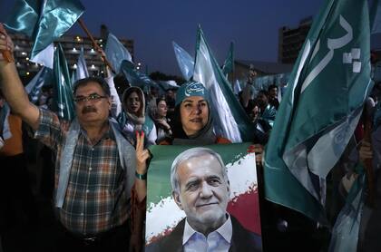 Partidarios del candidato reformista a las elecciones presidenciales de Irán, Masud Pezeshkian, que se muestra en el cartel, asisten a un mitin de campaña en Teherán