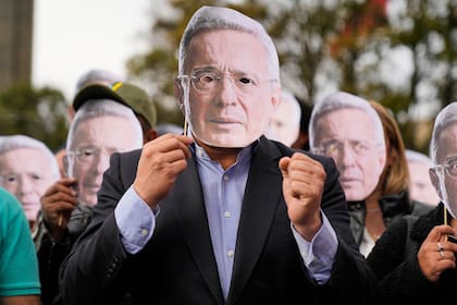 Partidarios del expresidente colombiano Álvaro Uribe sostienen recortes de su rostro frente al tribunal donde se dio el veredicto