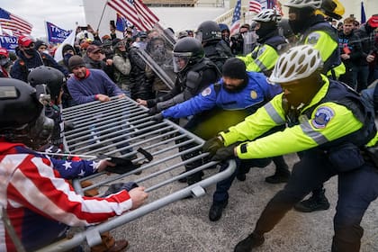 Partidarios violentos de Donald Trump tratan de rebasar una barrera policial en el Capitolio en Washington el 6 de enero del 2021.  (AP Foto/John Minchillo)