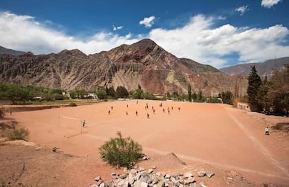 Partido de fútbol en un potrero de Purmamarca, rodeado de cerros.