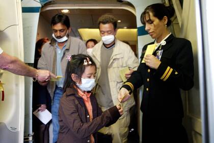 Pasajeros con cubrebocas que llegaron a Los Ángeles procedentes de Hong Kong durante el brote del SARS en 2003, recibieron folletos en los que se les aconsejaba vigilar su salud durante 10 días