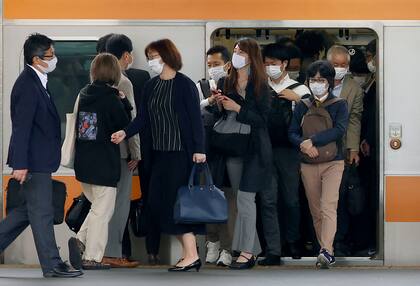 Pasajeros con mascarillas para protegerse del coronavirus salen de un tren en Tokio. Los casos en Japón siguen en aumento