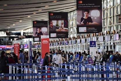 Pasajeros hacen cola en los mostradores del Aeropuerto Internacional Arturo Merino Benítez en Santiago de Chile, hoy