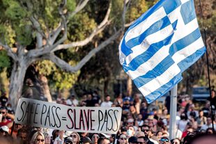 "Pase de seguridad=pase de esclavos", dice un cartel de manifestantes antivacunas en Nicosia contra el "pase verde" impuesto por el gobierno de Chipre; flamea una bandera de Grecia