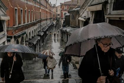Peatones en la calle Ruga dei Oresi en el centro de Venecia, Italia, durante mareas altas excepcionales que requirieron la activación de las barreras de Mose, el 22 de noviembre de 2022.