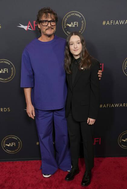 Pedro Pascall, con un conjunto amplio en tono azul y zapatillas, junto a Bella Ramsey, con traje y camisa negros