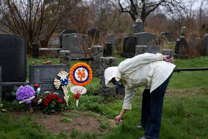 Peg Walter encuentra una piedra para colocar en la lápida de su difunto esposo en el cementerio All Faiths en el distrito de Queens de Nueva York