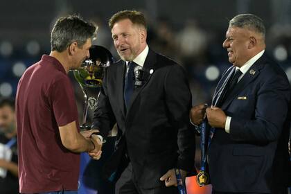 Pellegrino recibe el saludo de Alejandro Domínguez, presidente de la Conmebol, mientras Claudio Tapia espera para colgarle la medalla de campeón