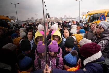 Grupos de familias que huyen de Ucrania hacen cola para abordar un autobús en el cruce fronterizo de Medyka, Polonia. Más de un millón de personas han huido de Ucrania tras la invasión de Rusia