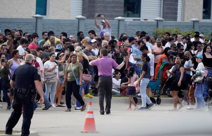 People gather across the street from a shopping center after a shooting Saturday, May 6, 2023, in Allen, Texas. (AP Photo/LM Otero)