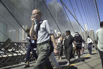 Un grupo de neoyorquinos escapan de Manhattan por el puente de Brooklyn, instantes después del colapso de las torres
