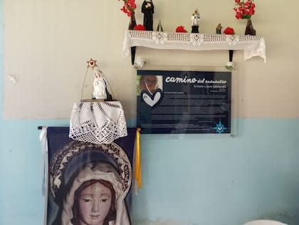 Pequeño altar en la posada El Fortín, en el Dique Campo Alegre. El cartel cuenta la historia del Camino a Salta. Hay detalles de la historia de Silvina y Diego, la pareja que tuvo la idea de abrir el camino tras la muerte de su hija Juana.