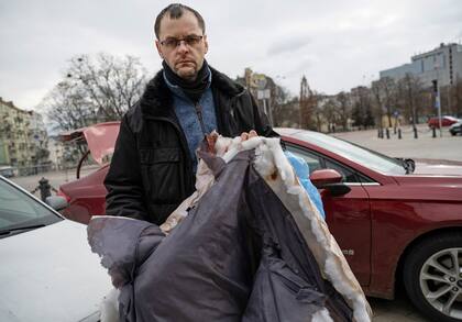 Perebyinis muestra la ropa ensangrentada y desgarrada de su esposa, que fue recuperada del lugar donde ella y sus hijos fallecieron
