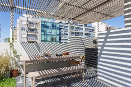 Pérgola hecha con listones de kiri (Malva Arquitectura). Plantas (Tou Tou Galpón). Mesa y bancos (Estudio Te). El piso de laja y el revestimiento de cerámicas partidas fueron construidos en obra, bajo el diseño del estudio de arquitectura.