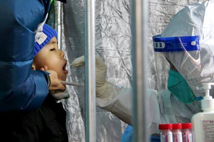 Personal de salud toma una muestra bucal a un niño para una prueba de COVID-19 