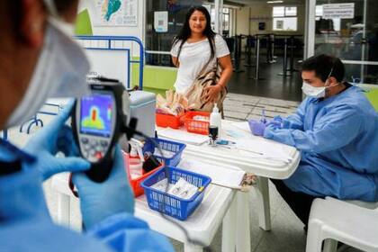 Personal de salud tomando la temperatura de una viajera en la frontera de Ecuador con Perú