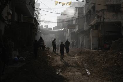 Personas caminan por una calle destruida tras una ofensiva de las fuerzas israelíes en el campamento de refugiados de Tulkarem, en la Cisjordania ocupada (AP Foto/Majdi Mohammed)