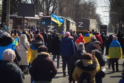 Personas con banderas ucranianas caminan hacia los camiones militares rusos durante una marcha contra la ocupación de Rusia, en Jersón, Ucrania, el domingo 20 de marzo de 2022