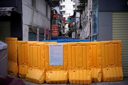 Personas con máscaras faciales caminan en un área residencial bloqueada por barreras en Wuhan, provincia de Hubei, el epicentro del brote de la enfermedad del coronavirus