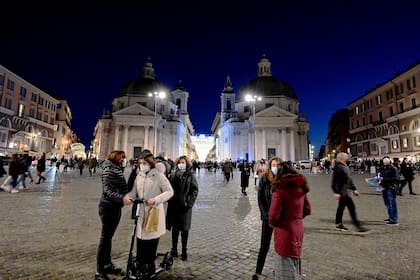 Personas con mascarilla caminan por la Piazza del Popolo en el centro de Roma el 13 de diciembre de 2020, durante la pandemia de coronavirus