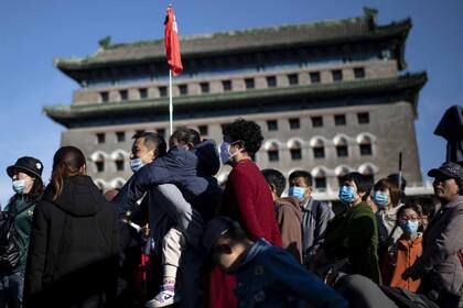 Personas con tapabocas llegan a la calle Qianmen para comprar durante el feriado nacional de la "Semana Dorada" hoy en Pekín