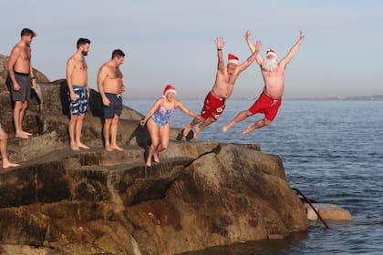 Personas con trajes navideños participan en el baño del día de Navidad en Forty Foot, Sandycove Dublín.