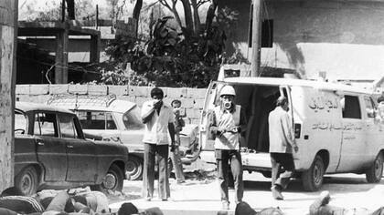 Personas cubriéndose el rostro para protegerse del olor a descomposición mientras comienzan a limpiar los restos de los miles de refugiados palestinos que fueron asesinados en la masacre de Sabra y Chatila